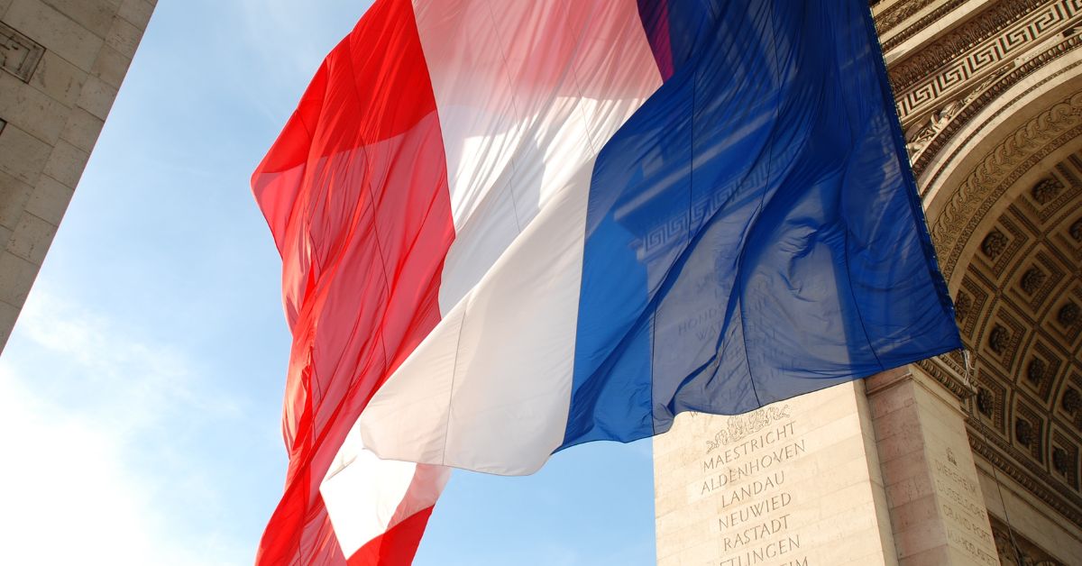 French flag waving near the Arc de Triomphe in Paris, symbolising France for a best forex brokers in France 2026 guide.